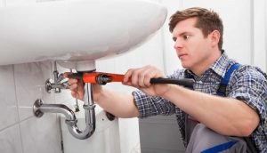 photo of a professional plumber tightening pipe