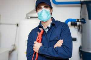 smiling-plumber-repairing-hot-water-heater-photo smiling plumber repairing hot water heater photo